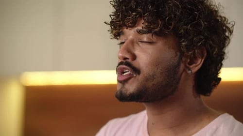 Man Enjoys Eating a Hamburger Indoors