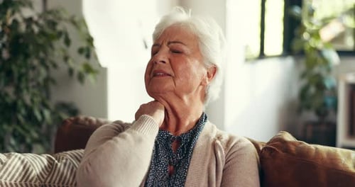 Senior Woman Massaging Sore Neck in Living Room