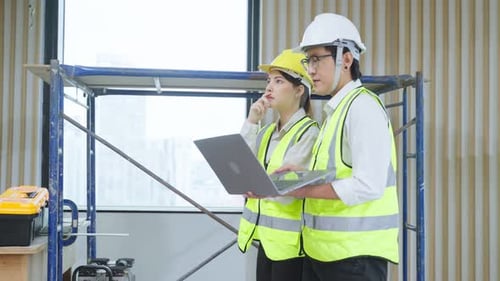 Asian young businessman and businesswoman working in construction site.