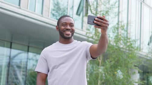 African American Man Holding Smartphone Having Video Chat on Urban Street in City Guy Blogger