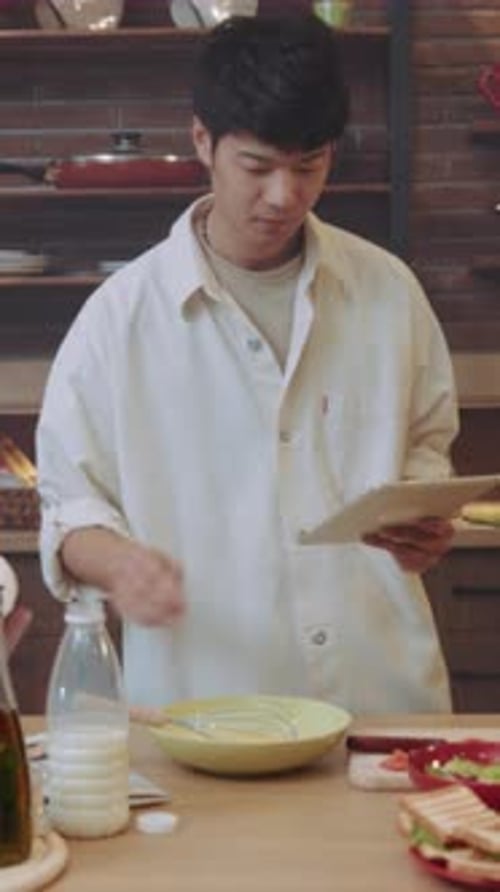 Young Man Cooking with Tablet in Sunny Kitchen
