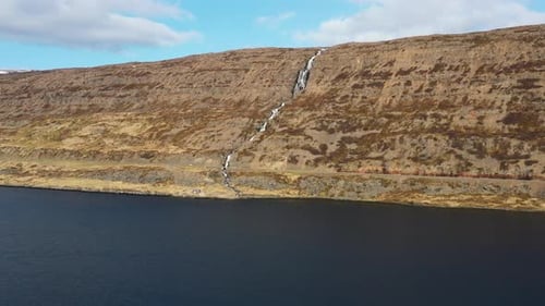 Vue aérienne de l'eau tombant au-dessus d'une cascade dans un mur de montagne sec en Islande.