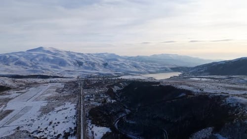 Winter landscape showcasing mountains and a lake under a serene sky in a remote area.
