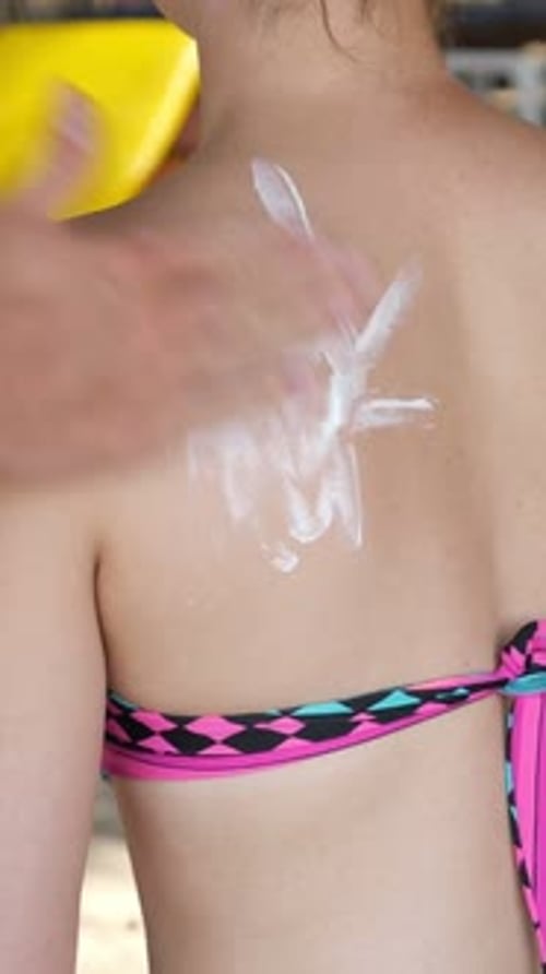 Frau trägt Sonnencreme am Strand auf Frau verwendet Sonnencreme bei Outdoor-Aktivitäten an der Küste zum Schutz