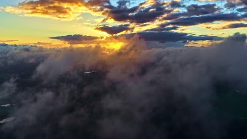 Sunlight breaks through dramatic clouds above a rolling cloud layer, casting golden light across