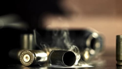 Smoking Bullets and Gun on Dark Table