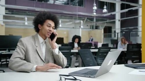 Young Adult Talking on Phone in Busy Office