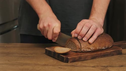 Man slicing crusty bread on wooden cutting board