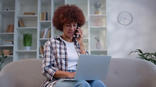Woman Working on Laptop While Talking on Phone