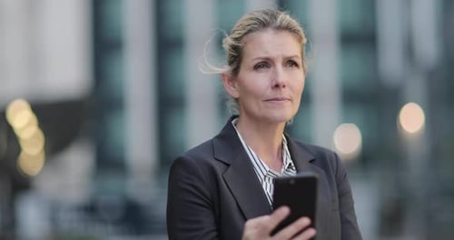 Businesswoman outdoors in city using smartphone