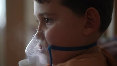 Sick Little Boy Receiving Respiratory Treatment with Nebulizer Mask Closeup Side View of Little Sick