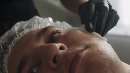 Tratamientos de belleza La cosmetóloga limpia la piel de la cara del cliente masculino