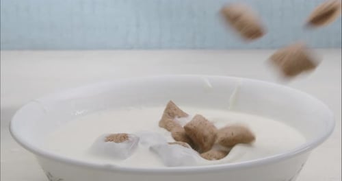 Cereal Pieces Falling into Bowl of Milk