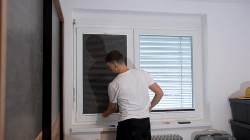 Man installing pleated blinds on an interior window