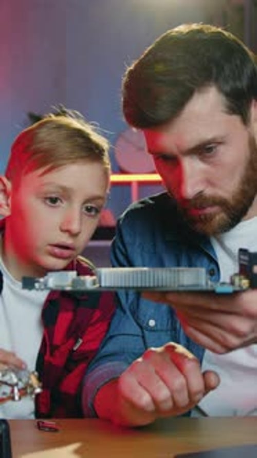Boy and Man Examine Computer Parts Together Indoors