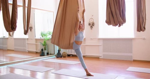 Woman Doing Splits in Aerial Yoga Hammock in Studio
