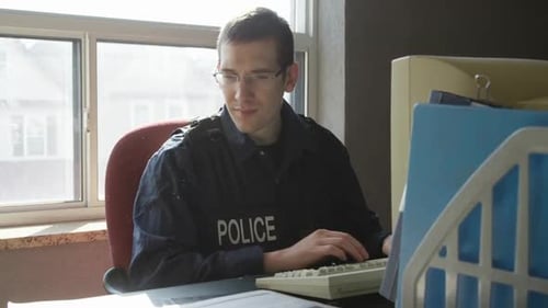 Man Wearing Police Uniform Types at Computer