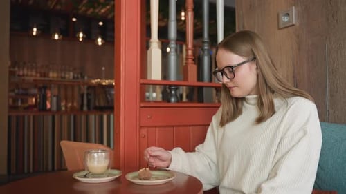Side View of Woman in Glasses Enjoying Dessert in Cozy Cafe Setting