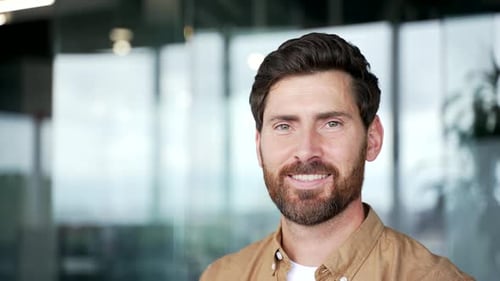 Portrait of smiling handsome businessman standing at workplace in a business office.