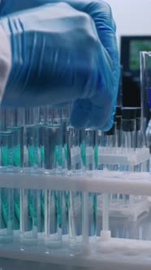 Close Up of Scientist Putting Test Tubes with Blue Liquid in Rack