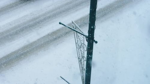 Blick von oben auf ein Auto, das während eines Schneesturms im kalten Winter in Zeitlupe vorbeifährt
