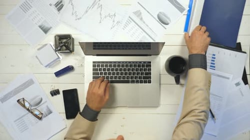 Male Hands of Manager Typing Text on Laptop Keyboard at White Desk Top View Arms of Young