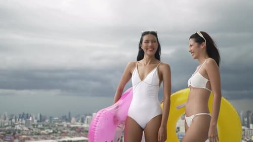 Female friends spend leisure activity at rooftop swimming pool.