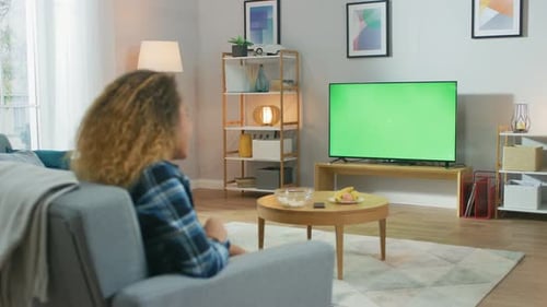 Girl Sitting At Home Sitting on a Couch, Watching Green Chroma Key Screen, Relaxing. Man in a Cozy