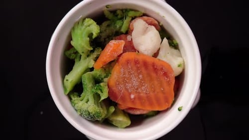 Rotating bowl filled with frozen mixed vegetables