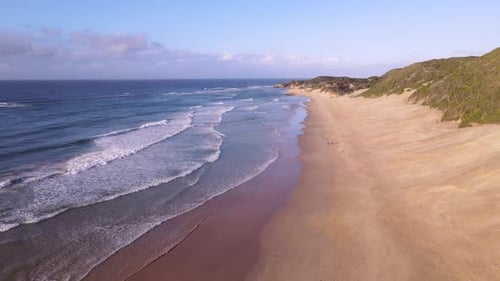 Drone Flying Along Coastline with People Seen Walking