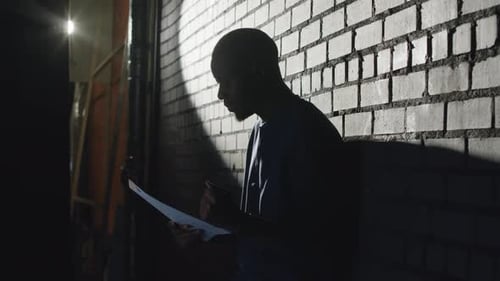 Adult Standing in Dark Alleyway with Document