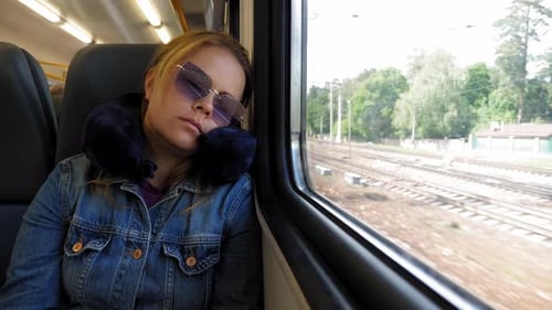 A Tired Woman is Sleeping on the Train with a Travel Pillow Around Her Neck