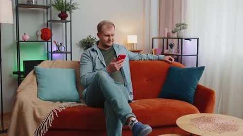 Man Relaxing on Couch Using Smartphone Indoors