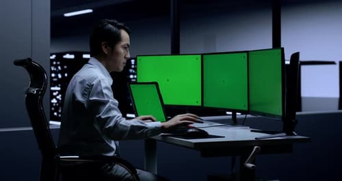 Männlicher Programmierer mit Greenscreen-Tablet tippt auf Greenscreen-Desktops im Serverraum