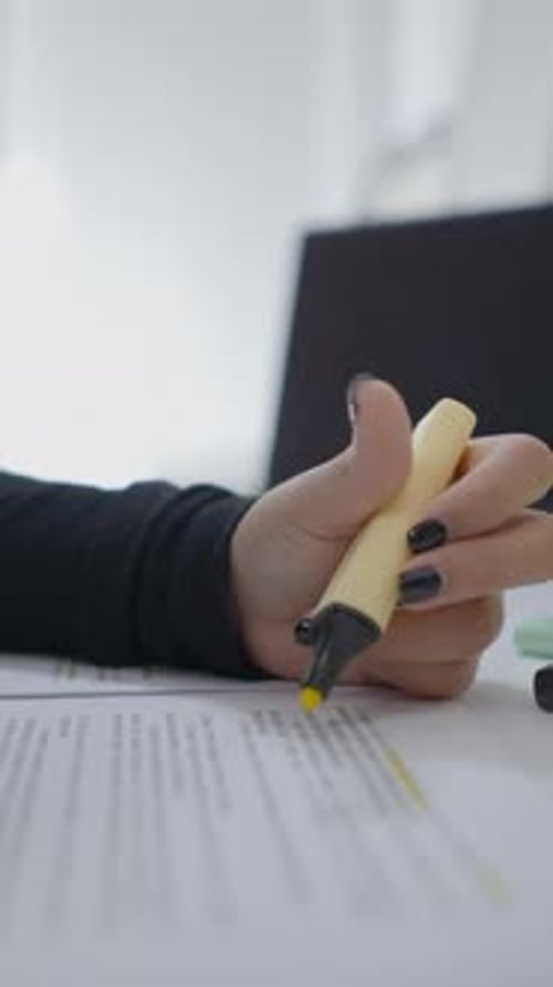Close Up Shot of an Unrecognizable Young Girl Sitting at a Desk and Highlighting Some Documents