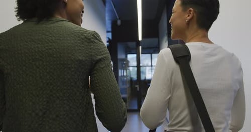 Happy diverse business people discussing work and walking at office