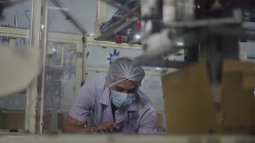 Man Inspecting Machinery in Factory with Tablet