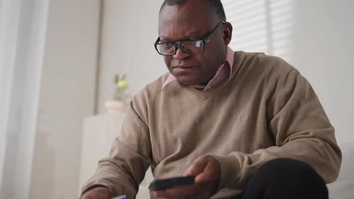 Man Using Phone and Taking Notes Indoors