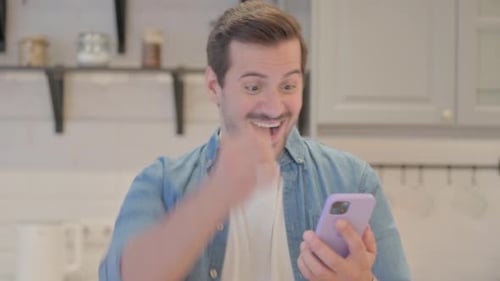 Excited Man Celebrates Success with Smartphone