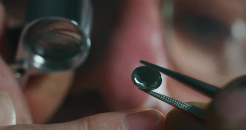 Slow motion macro close up of experienced goldsmith controlling a quality of precious gem, selecte
