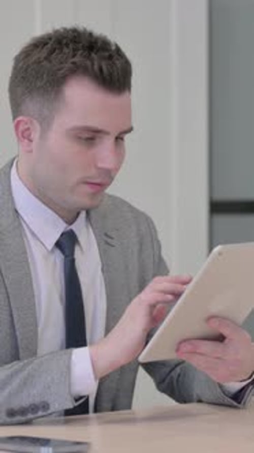 Young Adult Man Works on Tablet in Office Setting
