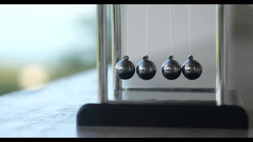 Gros plan d'une main conduisant un simple berceau de Newton