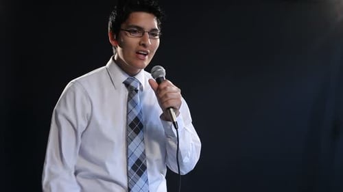 Enthusiastic young man gives speech into microphone