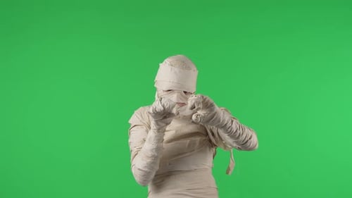 Vidéo à clé chromatique isolée sur écran vert capturant une momie debout, les bras croisés en train de se réveiller