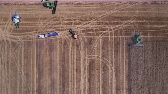 Straight down aerial view of a harvester truck and tractor all working ...