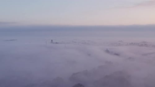 Aerial view of foggy sunrise over church and factory, Netherlands.