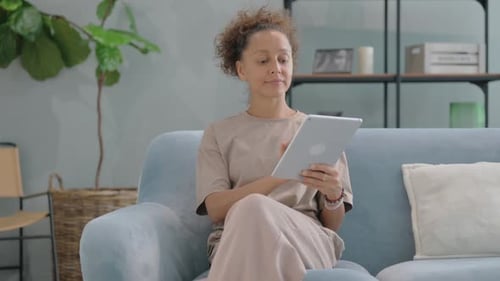 Woman Relaxing at Home Using Tablet on Couch