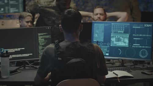 Back View of Cyber Security Military Worker Sitting in front of Computer