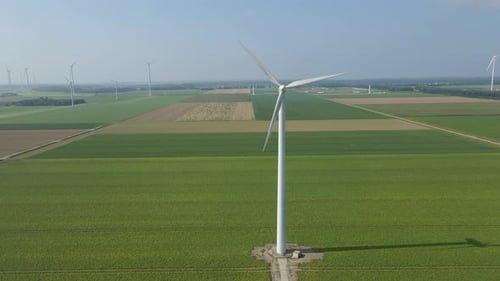 Jib up of spinning wind turbine in a large windmill park in green meadows