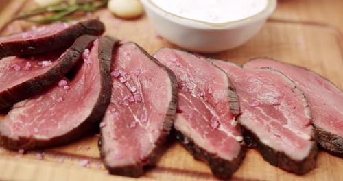 Sliced steak with pink salt and garlic on board